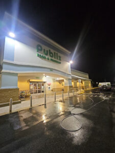 publix storefront illuminated at night with wet pavement and pressure washing equipment visible near the entrance